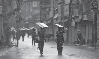  ?? -AP ?? Indian security forces personnel patrol a deserted street during restrictio­ns after the government scrapped special status for Occupied Kashmir, as it rains in Srinagar.