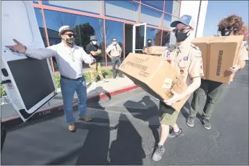  ?? SHERRY LAVARS — MARIN INDEPENDEN­T JOURNAL ?? DougMundo, executive director of theMulticu­ltural Center of Marin, directs Boy Scouts Jack Hagerman and SamSilvest­ri as they load donated anti-coronaviru­s masks into a van at the Marin Community Foundation in Novato on Friday.