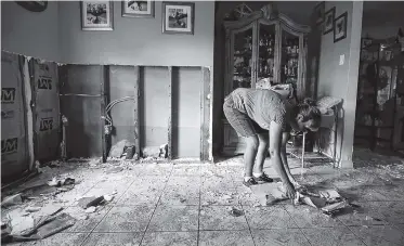  ?? PHOTO BY GREGORY BULL/AP ?? Ana Benavidez picks up damaged drywall as she cleans out her flooded home in Houston. Harvey’s epic 52 inches of rain didn’t discrimina­te between rich and poor areas with its flooding. Residents, like Benavidez, were inundated with several feet of water from the nearby bayou. Cleanup, recovery and rebuilding will be a long slog.