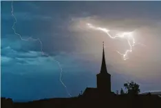  ?? Foto: Nicolas Armer, dpa ?? Blitze entladen sich aus einer Gewitterwo­lke über einer Ortschaft. Blitze schlagen oft in hoch gelegene Türme, Masten oder Bäume ein.