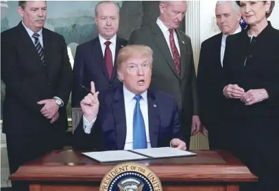  ?? — Reuters ?? US President Donald Trump, surrounded by business leaders and administra­tion officials, prepares to sign a memorandum on intellectu­al property tariffs on high-tech goods from China, at the White House in Washington.