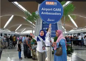  ??  ?? Helping hand: KLIA CARE ambassador Vive Nurhailiza Mohd Faizal Leong assisting a passenger during the disruption.