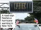  ??  ?? A road sign flashes a hurricane warning in New York