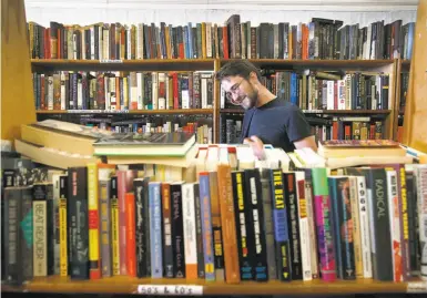  ?? Paul Chinn / The Chronicle ?? Cameron Graber scans the shelves of titles at Aardvark Books, which could close early next year if the building is sold.