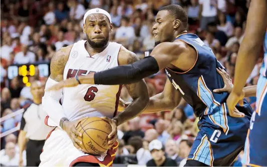  ??  ?? LEBRON JAMES, del Heat de Miami, recibe falta de Jeff Adrien, de los Bobcats de Charlotte, mientras penetra hacia el aro.