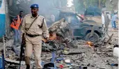  ??  ?? A Somali soldier walks near the wreckage of vehicles after a car bomb was detonated outside a popular hotel in Mogadishu on Saturday. —