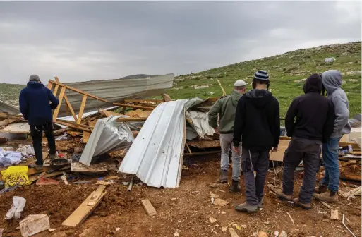  ?? (Yonatan Sindel/Flash90) ?? GATHERING AROUND damaged structures after Israeli security forces demolished Maoz Esther, March 21.