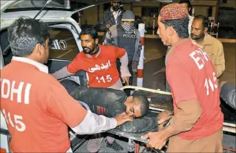  ?? Arshad Butt/Associated Press ?? Pakistani volunteers rush an injured man to a hospital Monday in Quetta, Pakistan, after gunmen opened fire and detonated explosive vests.