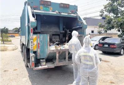 ??  ?? Garbage collectors making a pickup in Cumberland, St Catherine, one of the communitie­s under quarantine.