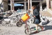  ?? — AFP ?? A girl pushes a cart loaded with a jerrycan while walking past the rubble of a building that was destroyed during Israeli bombardmen­t in Rafah on Wednesday.