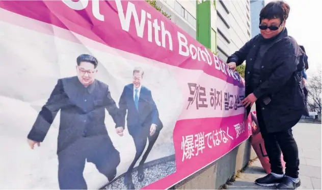  ?? Associated Press ?? ↑ A woman displays a banner showing a photo of Kim Jong Un and Moon Jae-in to wish for peace on the Korean Peninsula, in Seoul, South Korea, on Tuesday.