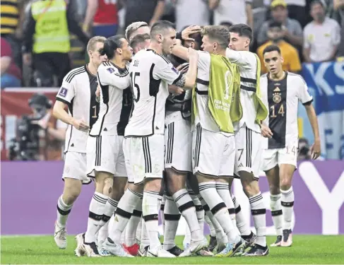  ?? ?? ↑ Germany players mob striker Niclas Fullkrug after his late goal earned a 1-1 draw against Spain to keep their World Cup hopes alive