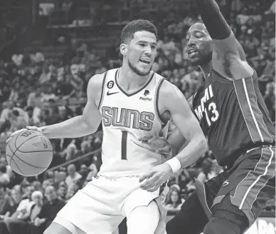  ?? MARTA LAVANDIER/AP ?? Phoenix Suns guard Devin Booker (1) dribbles as Miami Heat center Bam Adebayo (13) defends during the first half on Monday in Miami.