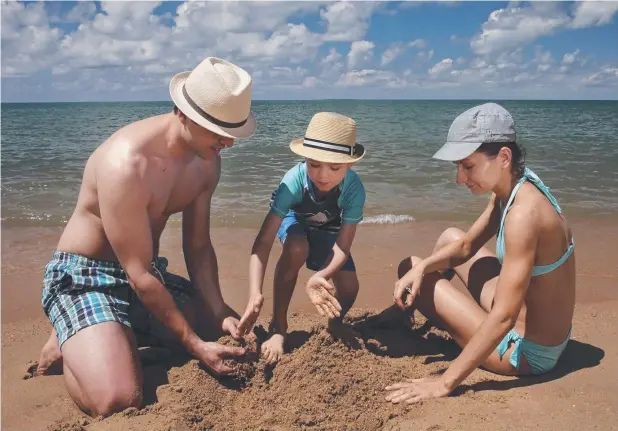  ?? Picture: ANNA ROGERS ?? SUN SEEKERS: Sydneyside­rs Tom Jakubiec, his wife Karolina and son Greg, 7, dig in to some holiday fun at Trinity Beach.