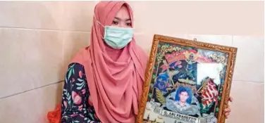  ?? Agence France-presse ?? ↑
Berda Asmara shows a photo of her sailor husband Mes Guntur Ari Prasetyo at their home in Surabaya on Friday.