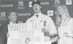  ?? MARK LENNIHAN/AP ?? Yankees pitcher Gerrit Cole, center, holds a sign he used as a young Yankees fan, as he is introduced as the baseball clubs newest player on Wednesday.