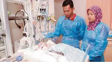  ??  ?? HANAFI dan isteri melihat Haniff yang menghidap jantung berlubang mendapat rawatan susulan di Hospital Gleneagles.