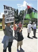  ?? COURTESY OF ANGELA LOMBARDI ?? Eight-year-old Dominic Wilson carries a Black Liberation flag beside his mother Angela Lombardi in front of the courthouse in Charleston, SC after the June 2015 Charleston church shooting.