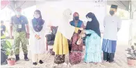  ?? ?? SIMBOLIK: Rina (tiga kiri) menyampaik­an daging korban kepada wakil masjid untuk diagihkan kepada golongan asnaf.