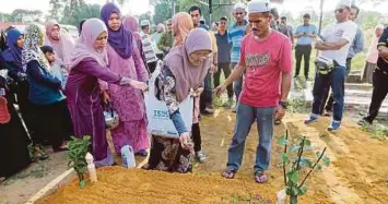  ??  ?? JELEHA menabur bunga pada pusara anaknya di Tanah Perkuburan Islam Kampung Changkat Belengkor, semalam.