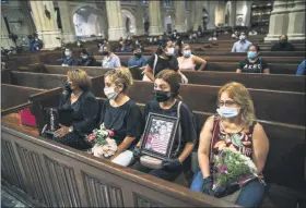  ?? EDUARDO MUNOZ ALVAREZ - ASSOCIATED PRESS ?? Mourners hold images of loved ones during the blessing of cremated remains of Mexicans who died from COVID-19 at St. Patrick’s Cathedral on Saturday in New York. The ashes were blessed before they were repatriate­d to Mexico.