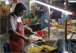  ??  ?? A woman takes a photo of a street art installati­on by artist Ernest Zacharevic. A cook stir-fries noodles at a street food stall in George Town, which oozes a hauntingly rustic charm, with colourful street art as much a draw as the historical...