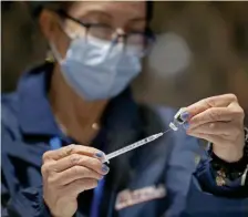  ?? MATT STONe / HeRALd STAFF FILe ?? KEEPING THE SHOTS MOVING: Sally McGowan of Cataldo Ambulance Service fills a needle with the Pfizer COVID-19 vaccine at the Hynes Convention Center on March 19.