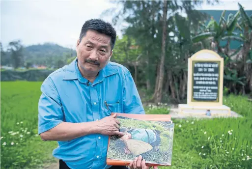  ?? HAU DINH/THE ASSOCIATED PRESS ?? My Lai massacre survivor Tran Van Duc with a photo taken by U.S. army photograph­er Ron Haeberle of his mother, Nguyen Thi Tau, who was killed in the massacre.