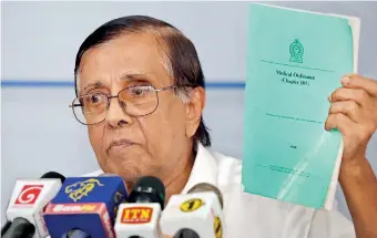  ??  ?? Prof. Goonaratna holds up the Medical Ordinance to make a point at the news conference. Pic by M.A. Pushpa Kumara