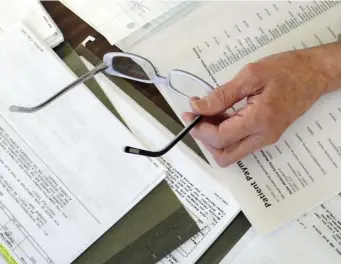 ?? AP FILE ?? STRESSFUL: Medical bills and other records are spread out on the kitchen table of a patient in Salem, Va.