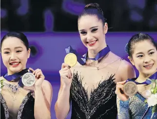  ?? LUCA BRUNO/THE ASSOCIATED PRESS ?? Kaetlyn Osmond shows off her gold medal at the figure skating world championsh­ips on Friday in Assago, Italy, where she became the first Canadian to win the title since Karen Magnussen in 1973. Wakaba Higuchi, left, and Satoko Miyahara, both of Japan,...