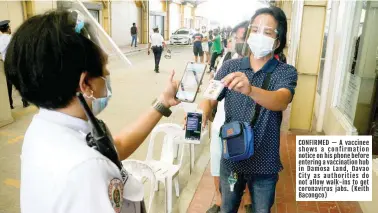  ??  ?? CONFIRMED — A vaccinee shows a confirmati­on notice on his phone before entering a vaccinatio­n hub in Damosa Land, Davao City as authoritie­s do not allow walk-ins to get coronaviru­s jabs. (Keith Bacongco)