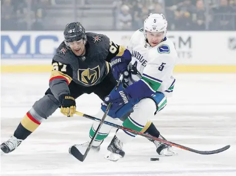  ?? JOHN LOCHER/THE ASSOCIATED PRESS ?? Vegas Golden Knights left winger Max Pacioretty and Canucks defenceman Derrick Pouliot vie for the puck during the first period on Wednesday night in Las Vegas. Pouliot made a few gaffes during the game, but the Canucks survived them to win in overtime.