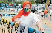  ?? Picture: REUTERS/ WILLY KURNIAWAN ?? HELPING HAND: A woman puts cloth face masks on a string to dry before distributi­ng it for free around the neighbourh­ood in Indonesia