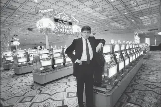  ?? ANGEL FRANCO / NEW YORK TIMES FILE (1990) ?? Donald Trump leans on a bank of slot machines on March 16, 1990, at his Taj Mahal casino in Atlantic City, N.J. Trump, now president of the United States, has long sold himself as a self-made billionair­e, but a New York Times investigat­ion found that he received at least $413 million in today’s dollars from his father’s real estate empire, much of it through tax dodges in the 1990s. Below, Trump holds a f lag atop Trump Tower in 1982.