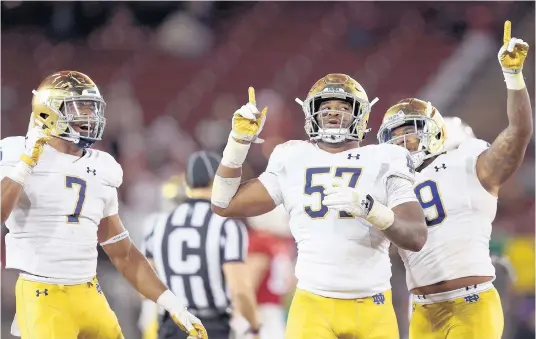  ?? GETTY PHOTOS EZRA SHAW/ ?? Jayson Ademilola (57) of the Notre Dame celebrates with Isaiah Foskey (7) and Justin Ademilola (9) after he records a sack against Stanford Cardinal in the second half on Saturday.