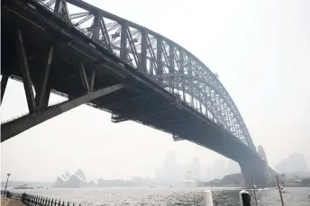  ?? — AFP photo ?? Smoke haze from bushfires shrouds the harbour bridge and city skyline in Sydney.