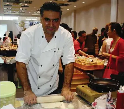  ??  ?? Bread maker: Ali rolling a ball of pita dough into a flat circle during the demonstrat­ion.