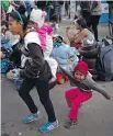  ?? RAMON ESPINOSA, AP ?? A Honduran migrant carrying a little girl and dragging another leave the shelter where they were staying in Tijuana, Mexico, on Friday.