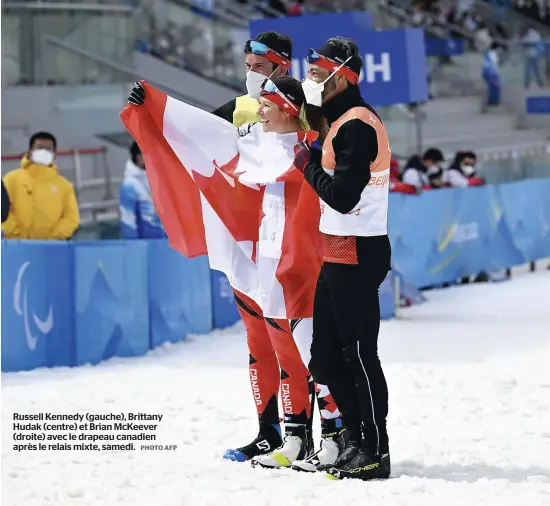  ?? PHOTO AFP ?? Russell Kennedy (gauche), Brittany Hudak (centre) et Brian McKeever (droite) avec le drapeau canadien après le relais mixte, samedi.