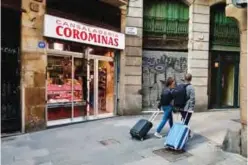  ??  ?? BARCELONA: Tourists pull their suitcases as they pass by a butcher shop of El Gotic neighborho­od, in Barcelona.— AFP