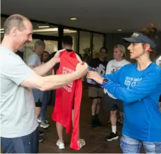  ?? John Colombo/For the Post-Gazette ?? Club member Greg Bump, left, of Squirrel Hill, receives his 2024 run club shirt from Kim Lambert before a group run in the neighborho­od.