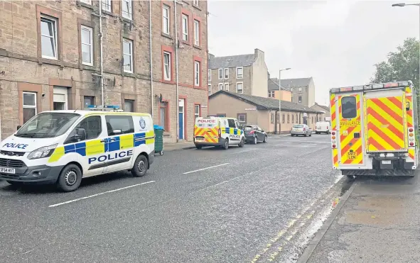  ??  ?? Above and below, police vehicles and the ambulance service at the scene of the raid in Tannadice Street.