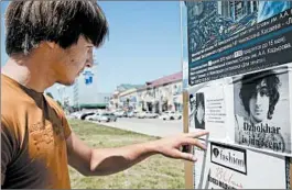  ?? ELENA FITKULINA/GETTY-AFP PHOTO ?? Even as U.S. and Russian agents probe the Boston bombings, a man in Chechnya’s capital, Grozny, reads a placard in support of bombing suspect Dzhokhar Tsarnaev last week.