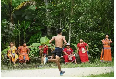  ?? — AP ?? Show ofstrength: A man running in the 10K competitio­n as Ngabe-Bugle women look on during the second edition of the Panamanian indigenous games in Piriati, Panama.