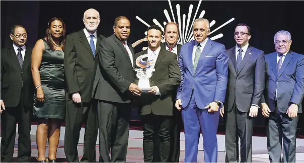  ?? FOTO CORTESÍA ERNESTO BELTRÉ | DISEÑO JULIO ANÍBAL RAMÍREZ ?? El Ministro de Deportes, Danilo Díaz, entrega la estatuilla que acredita a Audrys Nin Reyes como el Atleta del Año 2018. Le acompañan una serie de personalid­ades que asistieron a la Gala Olímpica.