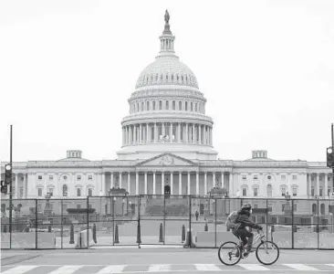  ?? PATRICK SEMANSKY/AP ?? A bicyclist rides past security fencing set up surroundin­g the U.S. Capitol in Washington on Friday, in response to the storming of the Capitol two days earlier by supporters of President Donald Trump.