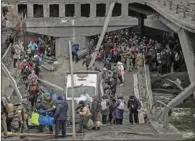  ?? ?? People cross a destroyed bridge as they evacuate the city of Irpin, northwest of Kyiv, during heavy shelling on Saturday. (AFP)