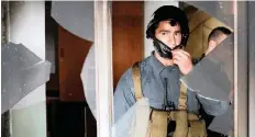  ?? | Reuters ?? A POLICEMAN looks out from a broken window after an attack in a Sikh religious complex in Kabul, Afghanista­n, yesterday.