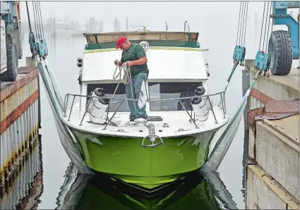  ?? SEAN D. ELLIOT/THE DAY ?? Mike Lamperelli readies dock lines Friday at Spicer’s Marina in Noank as his restored 1975 Ray Hunt-designed Chris-Craft 30-foot Sportsman boat floats for the first time in nearly 20 years. Lamperelli has spent about $120,000 getting the rare boat in...